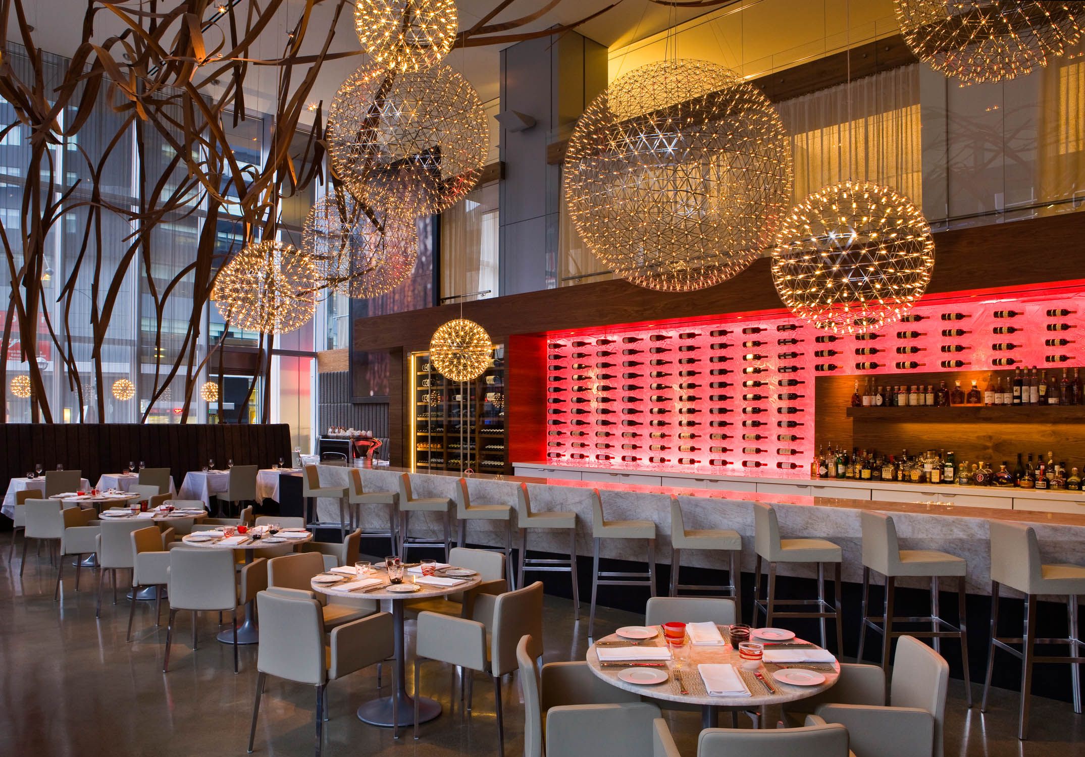 Aria Ristorante’s elegant dining room with sculptural globe lights and an illuminated wine wall